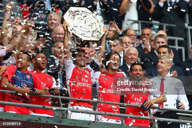 Mikel Arteta of Arsenal holds up the trophy watched by Arsene Wenger, manager of Arsenal after the FA Community Shield match between Manchester City...
