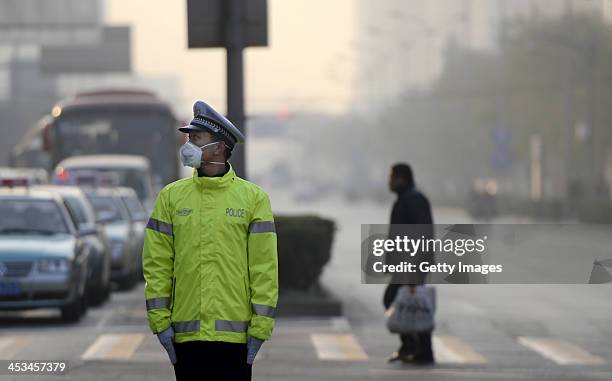 Traffic policeman wearing masks stands on a road on December 3, 2013 in Jinan, China. China Meteorological Administration issued a yellow warning on...