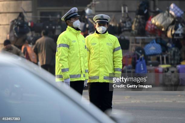 Two traffic policemen wearing masks stand on a road on December 3, 2013 in Jinan, China. China Meteorological Administration issued a yellow warning...