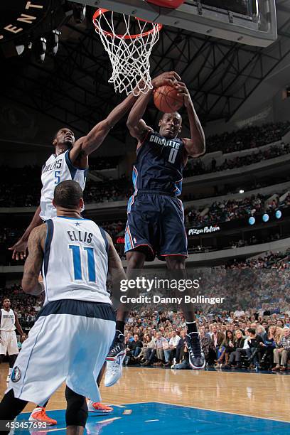 Bismack Biyombo of the Charlotte Bobcats rebounds the ball against Bernard James of the Dallas Mavericks on December 3, 2013 at the American Airlines...