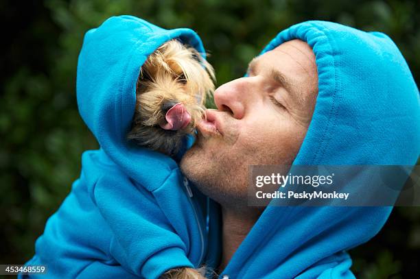 Uomo Baciare la migliore amico cane al parco coordinata con cappuccio blu