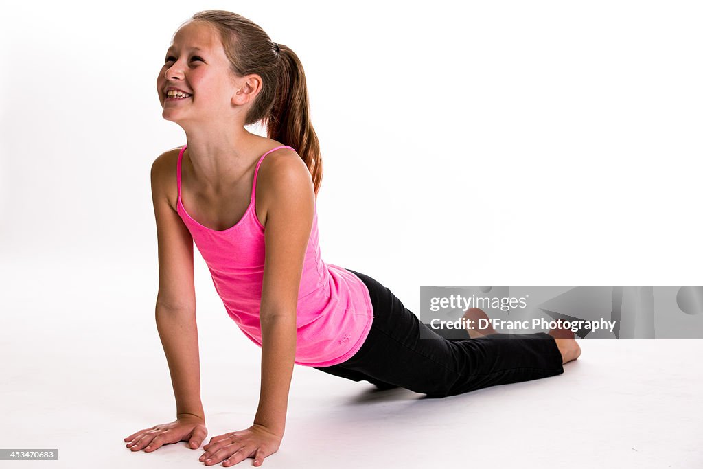 A Young Girl In Black Pants And Pink Top Does Yoga High-Res Stock