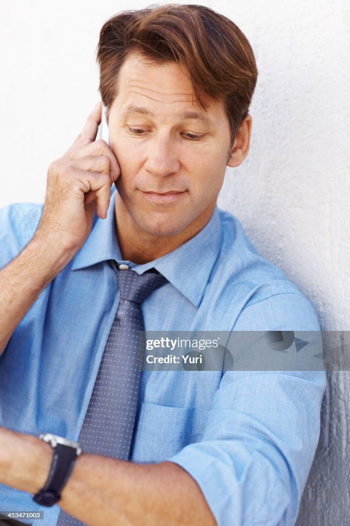 Busy businessman using cellphone and looks at his watch