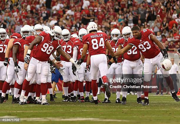 Tight end Rob Housler of the Arizona Cardinals high-fives defensive end Frostee Rucker and defensive end Calais Campbell as they are introduced to...