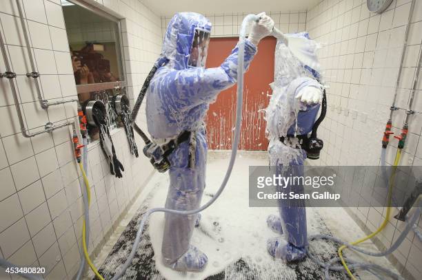 Nurse and a doctor for tropical medicine wearing isolation suits demonstrate the decontamination procedure as part of ebola treatment capability at...