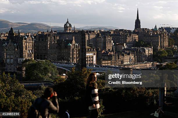 Tourists stand at the top of Calton Hill and look out towards the spire of St. Giles Cathedral, center, and The Hub, right, formerly Victoria Hall,...