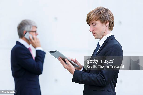 Two men in suits with iPad and mobile phone on August 07, 2014 in Berlin, Germany.