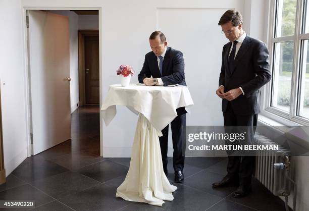 Australian Prime Minister Tony Abbott accompanied by his Dutch counterpart Mark Rutte signs a condolence register during his visit to Rutte's...