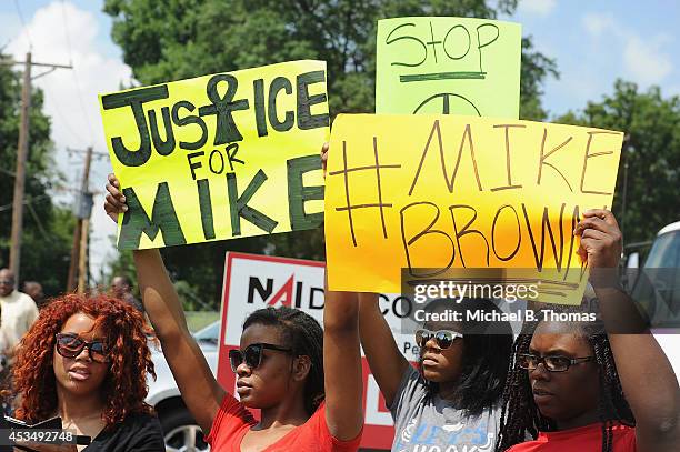 Women hold signs during a protest of the shooting death of 18-year-old Michael Brown by a Ferguson police officer, outside Ferguson Police Department...