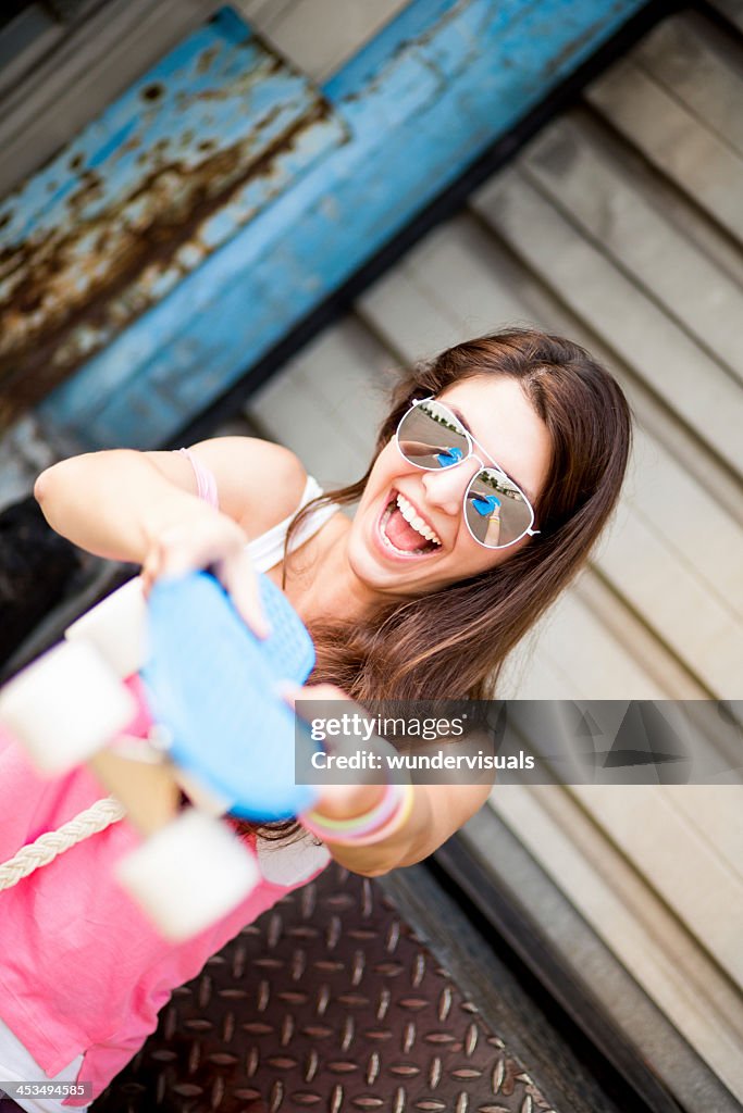 Cheerful girl with skateboard smiling at camera