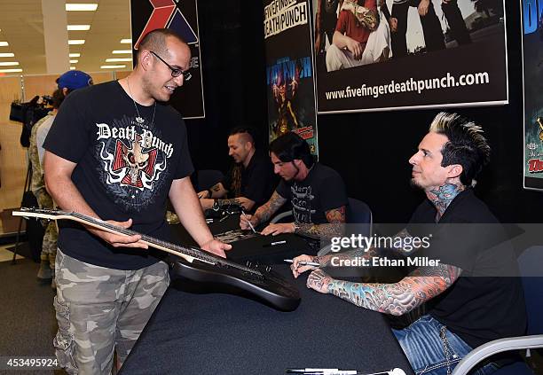 Airman 1st Class Jose Collazo gets a guitar signed by drummer Jeremy Spencer of Five Finger Death Punch at Nellis Air Force Base as the band...