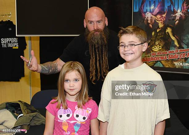 Rachel Allen and her brother Joel Allen pose for a photo with bassist Chris Kael of Five Finger Death Punch at Nellis Air Force Base as the band...