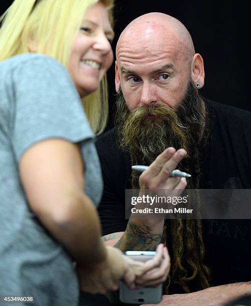 Bassist Chris Kael of Five Finger Death Punch poses with a fan at Nellis Air Force Base as the band highlights its campaign to raise awareness about...