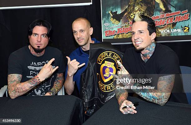 Retired Maj. Jason Regester poses for a photo with guitarist Jason Hook and drummer Jeremy Spencer of Five Finger Death Punch at Nellis Air Force...