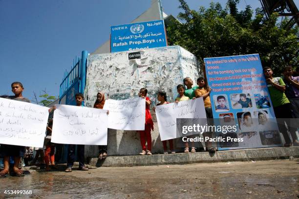 Palestinian children hold posters outside an UNRWA school during a protest against the killing of children in the southern city of Rafah, a week...