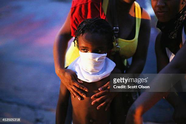 Child uses a rag to shield his face from tear gas being fired by police who used it to force protestors from the business district into nearby...
