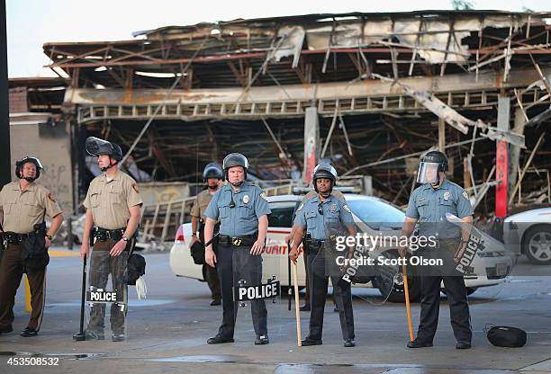 Police guard a Quick Trip gas station that was burned yesterday when protests over the killing of 18-year-old Michael Brown turned to riots and...