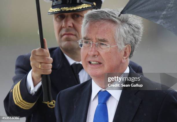 New British Defence Secretary Michael Fallon walks under rain with German Defence Minister Ursula von der Leyen upon his arrival at the German...