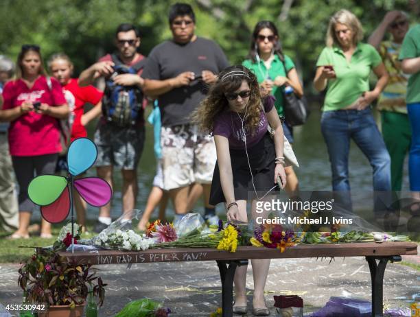 Annie Hochheiser of Cambridge, Massachusetts places flowers onto a fan memorial in honor of Robin Williams on the bench made famous by his movie...