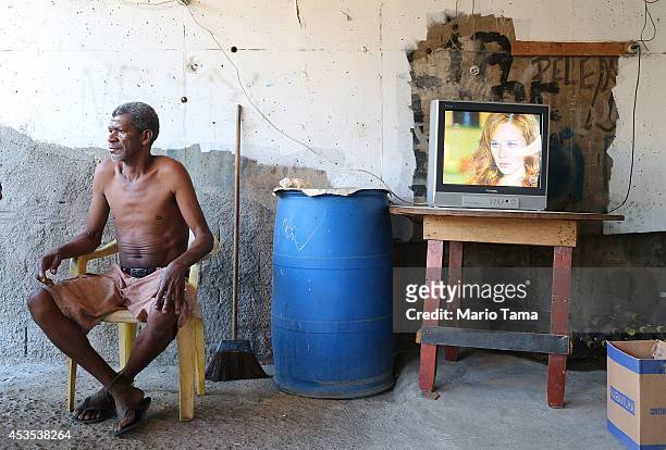 Man sits beneath an overpass as a soap opera plays in the occupied Complexo da Mare, one of the largest favela complexes in Rio, on August 12, 2014...