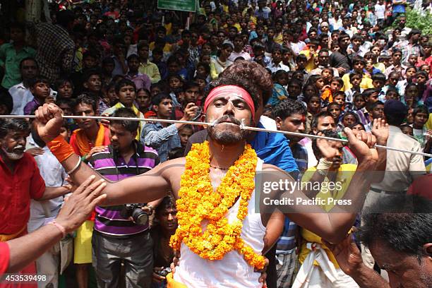 South Indian devotee gets his cheek pierced with a metal rod while participating in a religious procession to praise the Hindu goddess Shetala Mata...