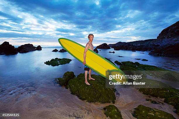 man holding surfboard - woolacombe surf stock pictures, royalty-free photos & images