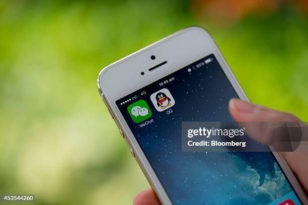 The icons for Tencent Holdings Ltd.'s messaging applications WeChat, left, and QQ are displayed on an Apple Inc. IPhone 5s smartphone in an arranged...