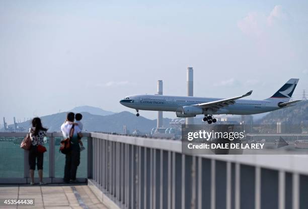 In this picture taken on August 10 people watch as a Cathay Pacific passenger plane prepares to land at Hong Kong's international airport. Hong Kong...