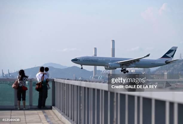 In this picture taken on August 10 people watch as a Cathay Pacific passenger plane prepares to land at Hong Kong's international airport. Hong Kong...