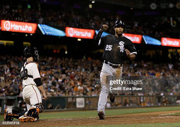 Moises Sierra of the Chicago White Sox celebrates as he crosses home plate in front of Buster Posey of the San Francisco Giants after he scored on a...