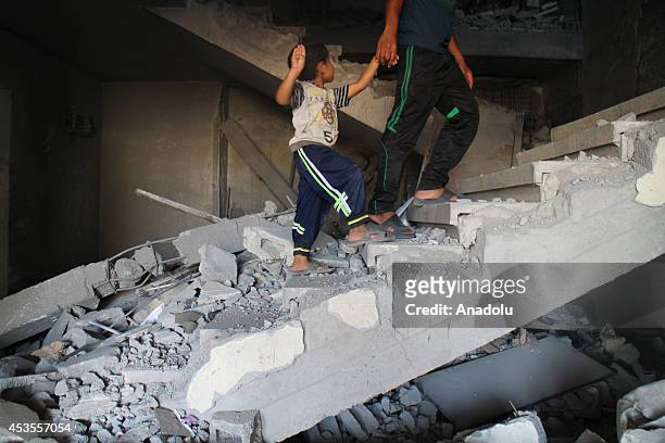Palestinian child with his brother are seen inside debris of the buildings destroyed by Israeli army as Palestinians get back to Beit Lahia to...