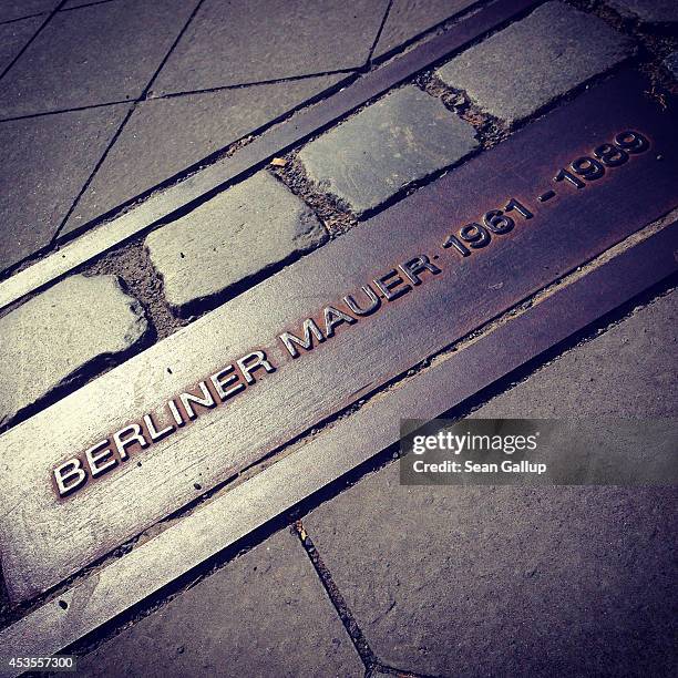 Plaque lies in cobblestones showing where the former Berlin Wall once stood at the Bernauer Strasse memorial on the 53rd anniversary of the...