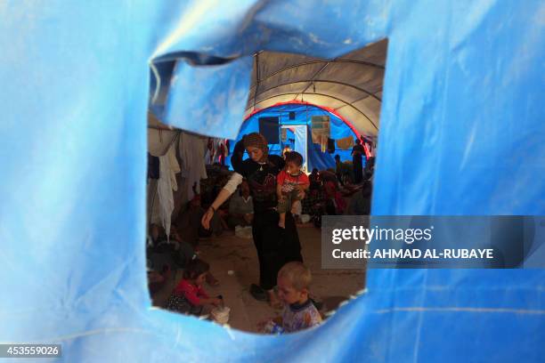 Displaced Iraqi Yazidis, who fled a jihadist onslaught on Sinjar, stand inside a tent after they took refuge at the Bajid Kandala camp in Kurdistan's...