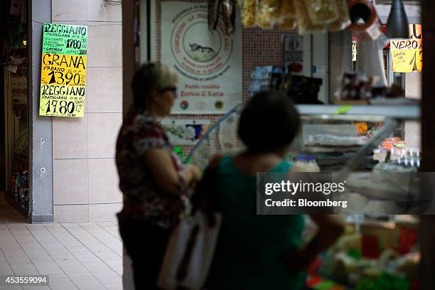 Signs displays the price in euros of Italian Reggiano Parmigiano and Grana Padano cheese as customers wait to be served at a delicatessen inside an...