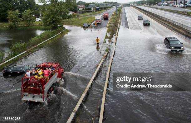 Members of the Bayshore Fire Department survey flood damage at Sunrise Highway following heavy rains and flash flooding August 13, 2014 in Bayshore,...