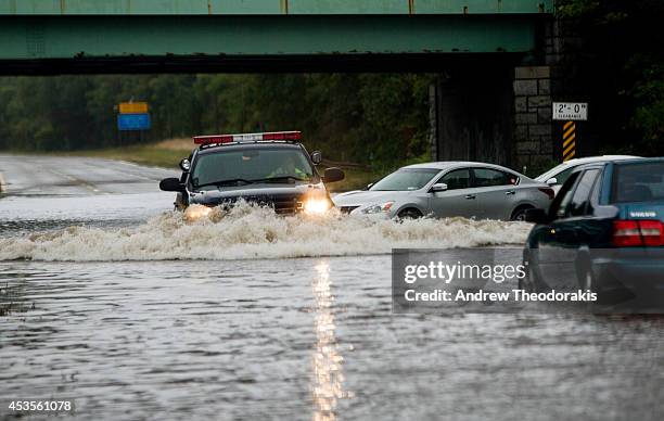 Police officer drives past flooded cars abandoned on the Southern State Parkway following heavy rains and flash flooding August 13, 2014 in Islip,...