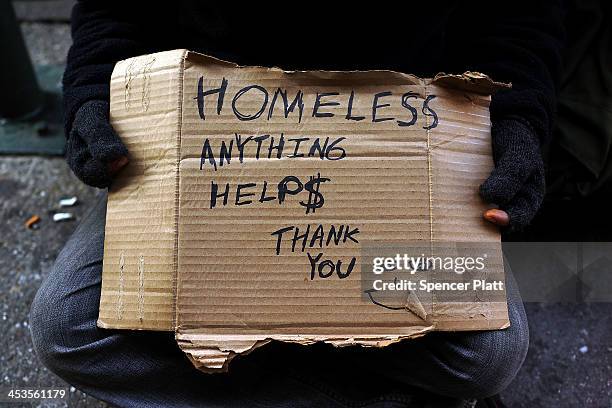 Person in economic difficulty holds a homemade sign asking for money along a Manhattan street on December 4, 2013 in New York City. According to a...