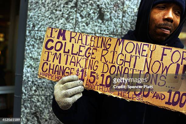 Person in economic difficulty holds a homemade sign asking for money along a Manhattan street on December 4, 2013 in New York City. According to a...