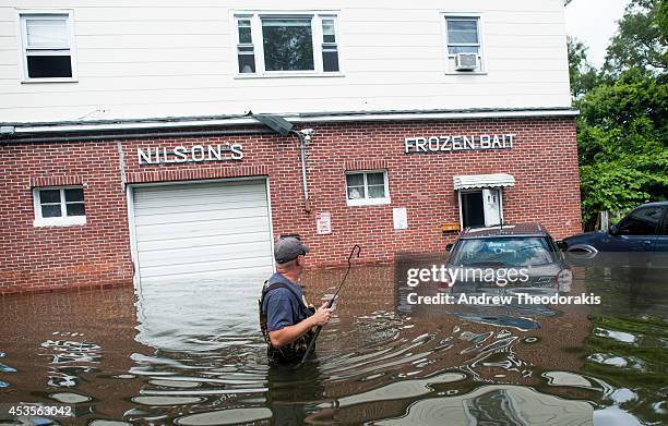 Chet Hingle wades in the water in front of his home on a flooded Reddington St. Following heavy rains and flash flooding August 13, 2014 in Bayshore,...