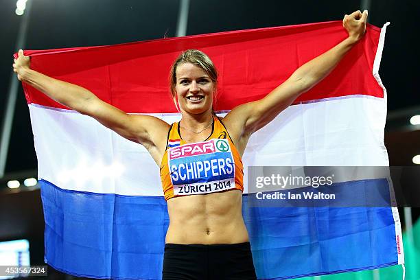 Dafne Schippers of the Netherlands celebrates with the Dutch national flag after claiming gold in the competes in the Women's 100 metres final during...