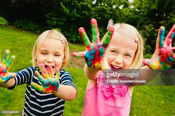 cute sisters having fun with finger paint - vingerverf stockfoto's en -beelden