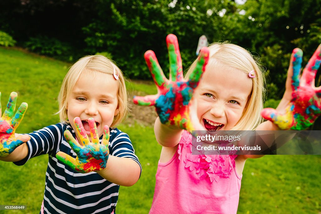 Cute sisters having fun with finger paint