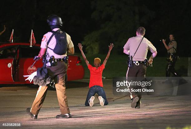 Police surround and detain two people in a car on August 13, 2014 in Ferguson, Missouri. Ferguson is experiencing its fourth day of unrest after...