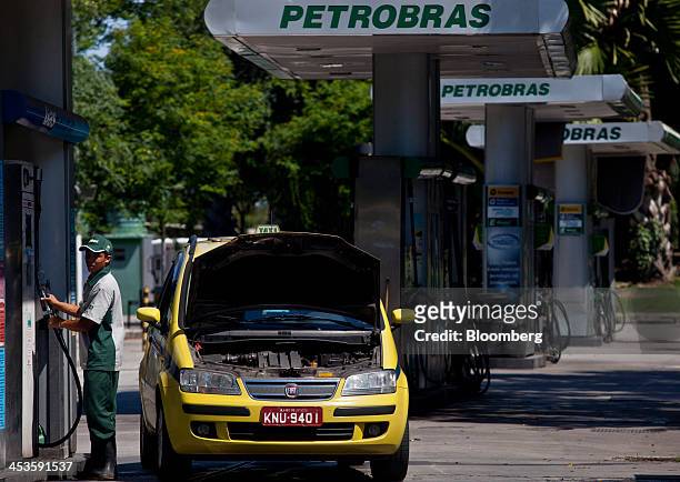 An attendant fills a taxi with natural gas at a Petroleo Brasileiro SA fueling station in Rio de Janeiro, Brazil, on Wednesday, Dec. 4, 2013....