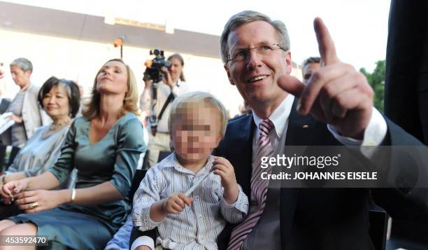 Germany's new President Christian Wulff gestures while his son Linus sits on his knees next to his wife Bettina, during the President's traditional...
