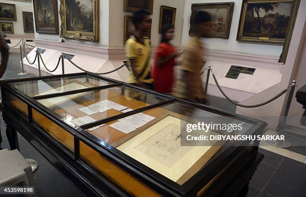 Indian visitors walk past displays of two artworks by Salvador Dali in Durbar Hall of The Victoria Memorial in Kolkata on August 14, 2014. The two...