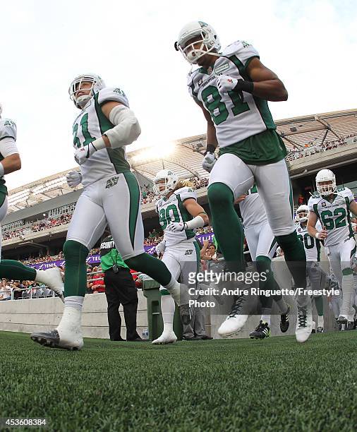 Samuel Hurl and Chaz Schilens the Saskatchewan Roughriders run onto the field during player introductions prior to playing against the Ottawa...