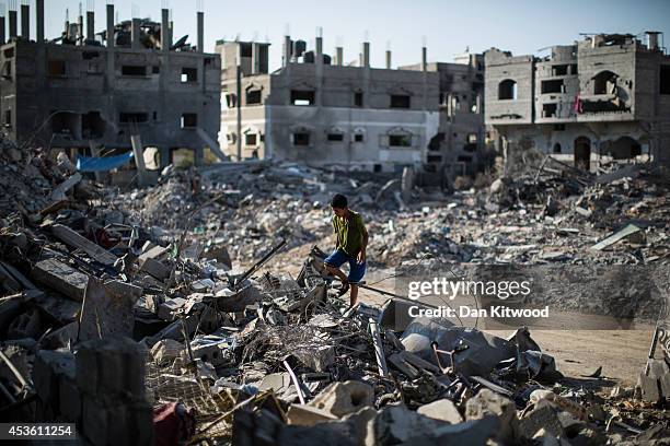 Young boy climbs through the rubble of a destroyed building on August 14, 2014 in Beit Hanoun, Gaza. A new five-day ceasefire between Palestinian...