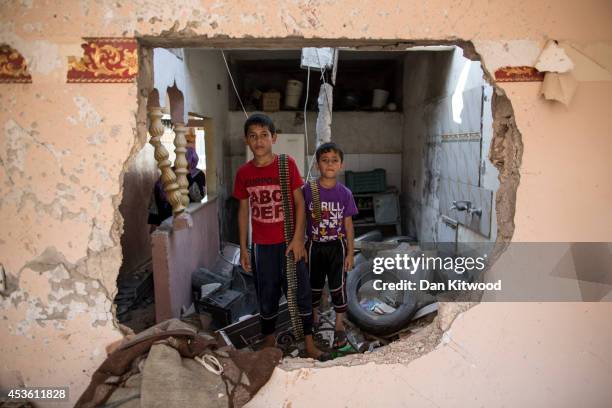 Two children stand in their demolished home holding ammunition on August 14, 2014 in Beit Hanoun, Gaza. A new five-day ceasefire between Palestinian...