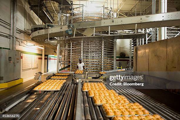 An employee taps the bottom of trays to to loosen the bread in pans at the Orlando Baking Co. In Cleveland, Ohio, U.S., on Wednesday, Aug. 13, 2014....